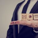 Retro style image of a businessman holding three wooden cubes with contact symbols - envelope, at sign and telephone - conceptual of communication and business support.